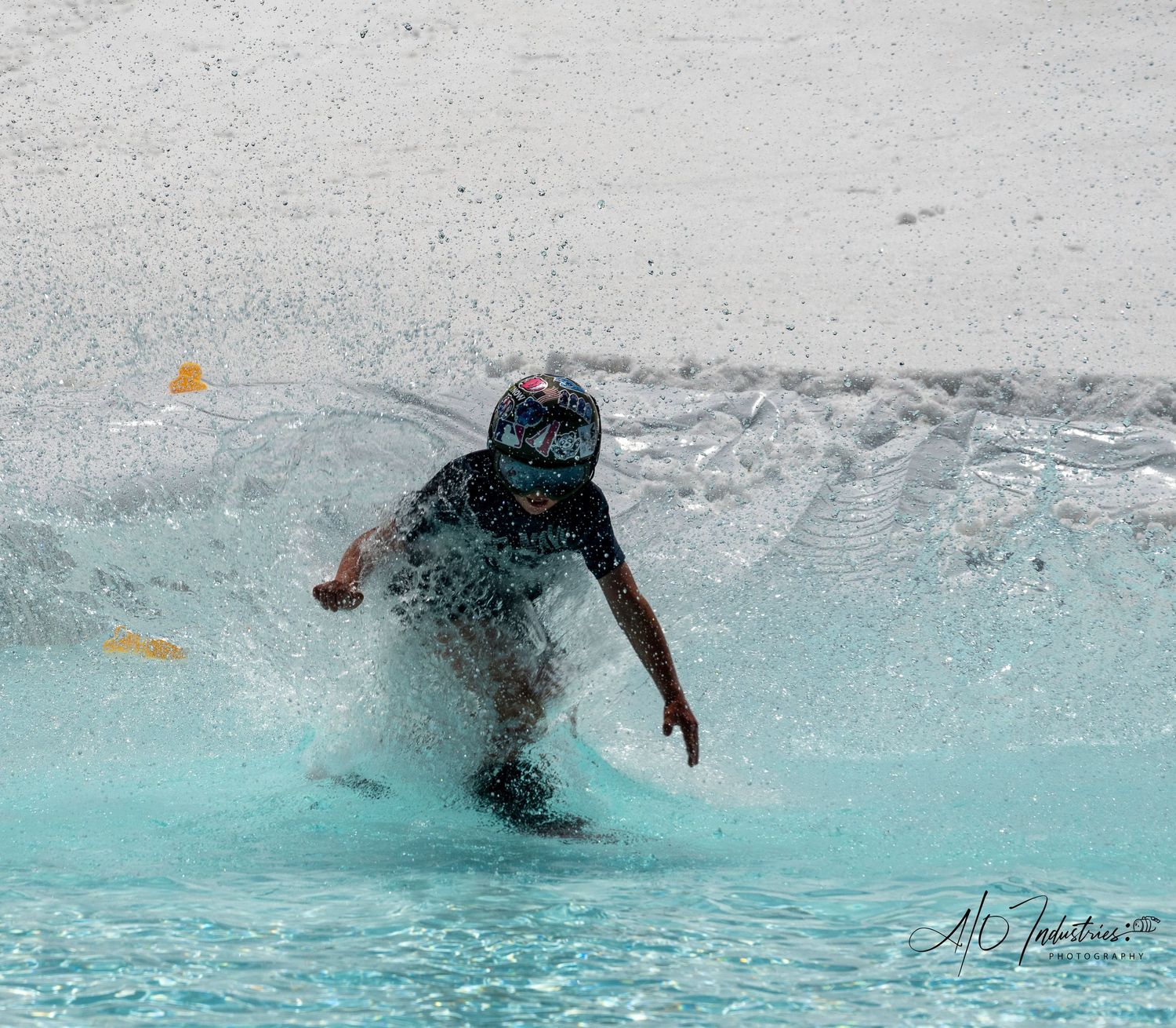 Skier splashes through bright blue water during pond skimming competition.