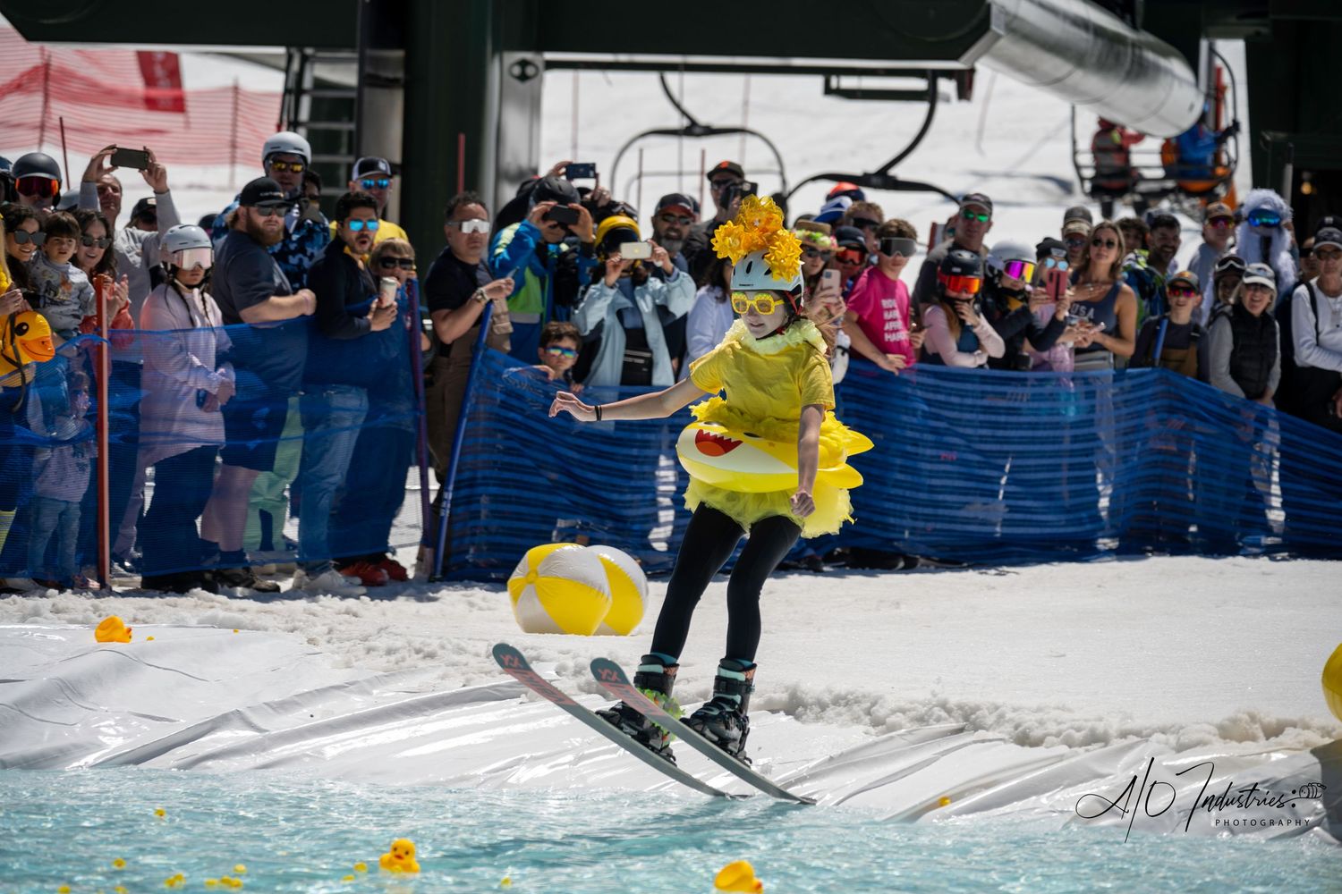 Skier in yellow outfit attempts to cross water pond during winter sports event.