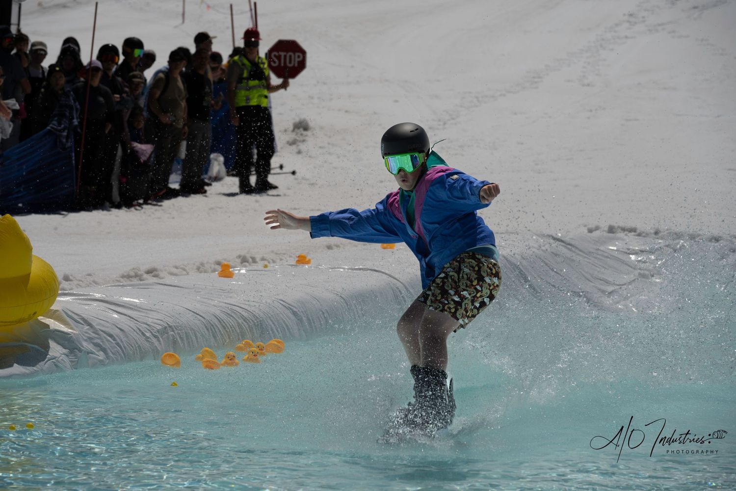 Snowboarder splashes through water during winter sports competition.