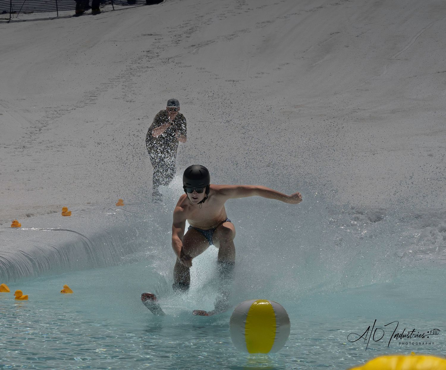 Participants attempt to skim across pool of water during winter sports event.