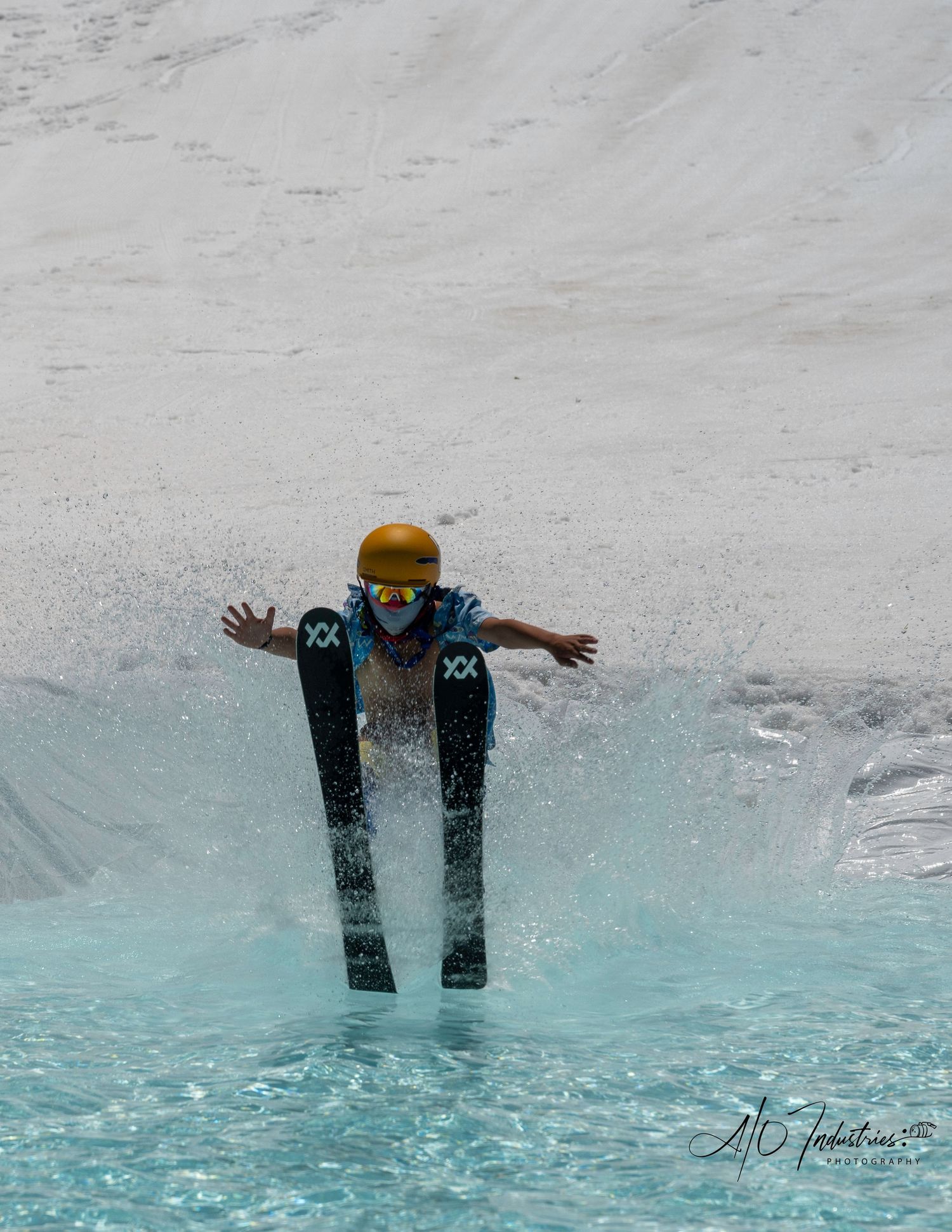 Skier with arms outstretched attempts to cross blue pool during winter competition.