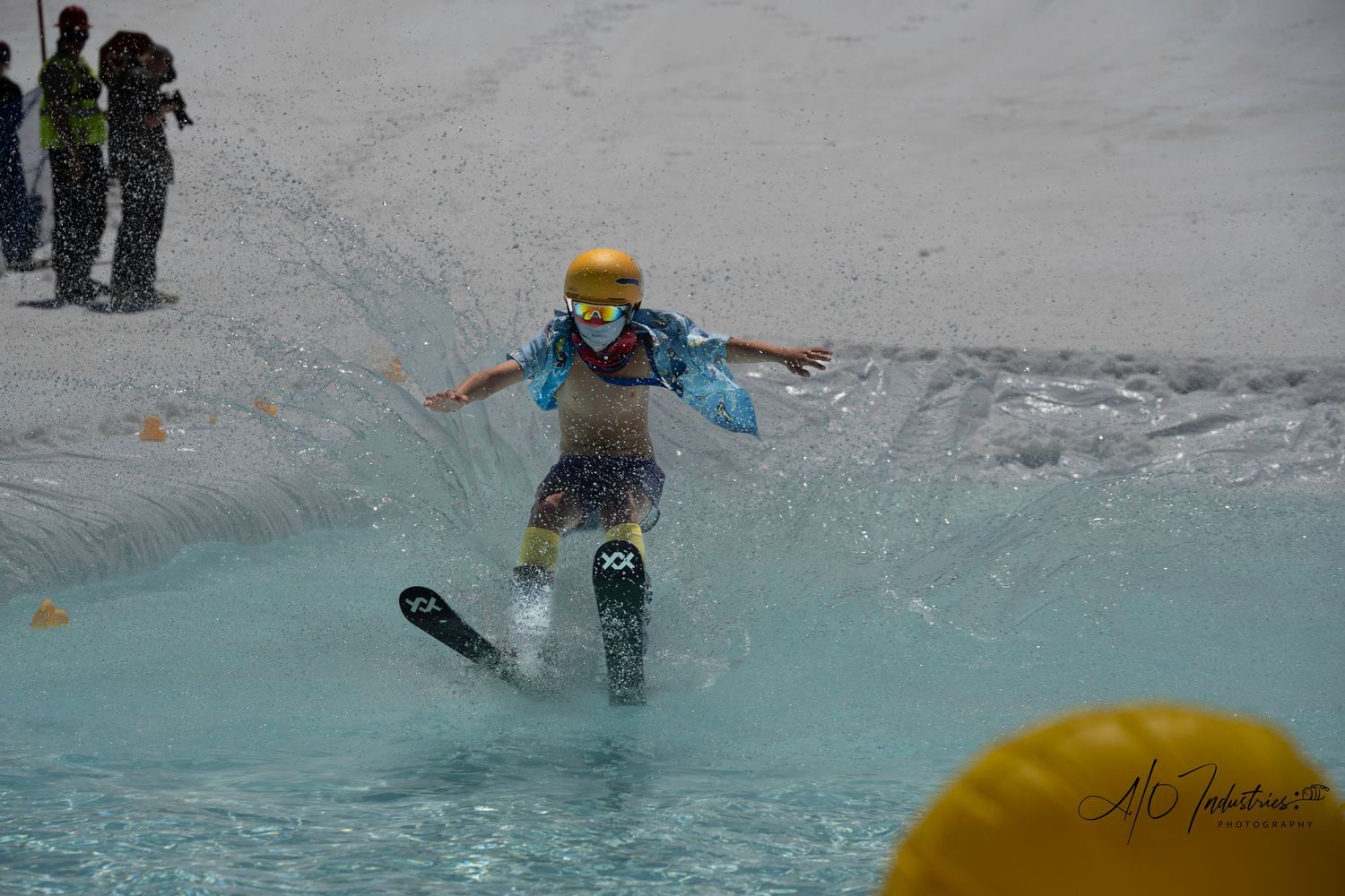 Young snowboarder attempts to cross blue pool during winter sporting event.