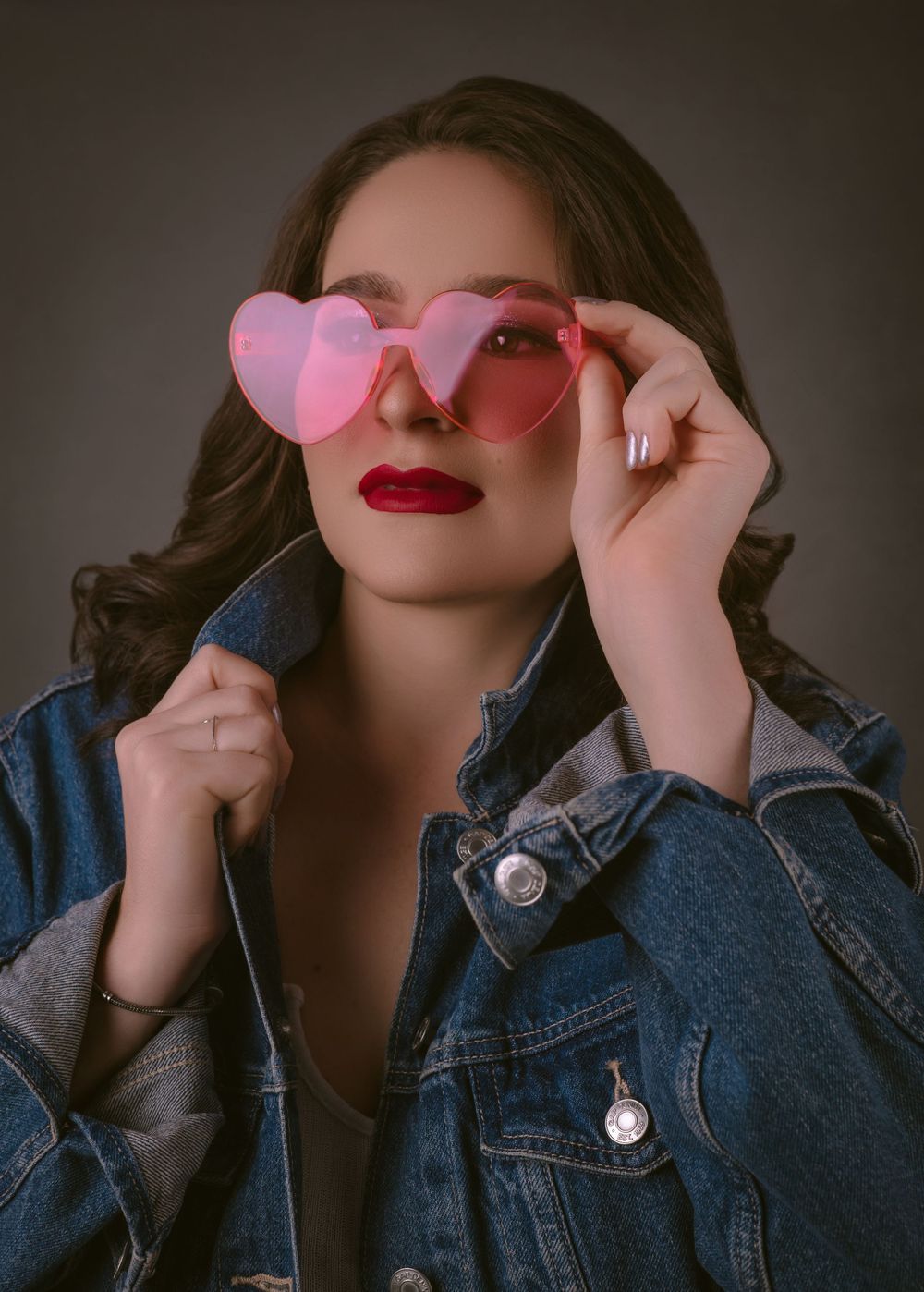 Retro-styled portrait with heart-shaped sunglasses and denim jacket.