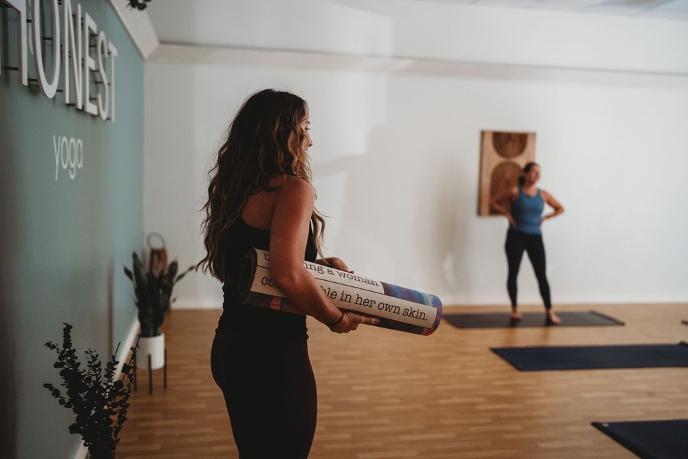 People working out in a bright fitness studio with hardwood floors and white walls during an exercise class.