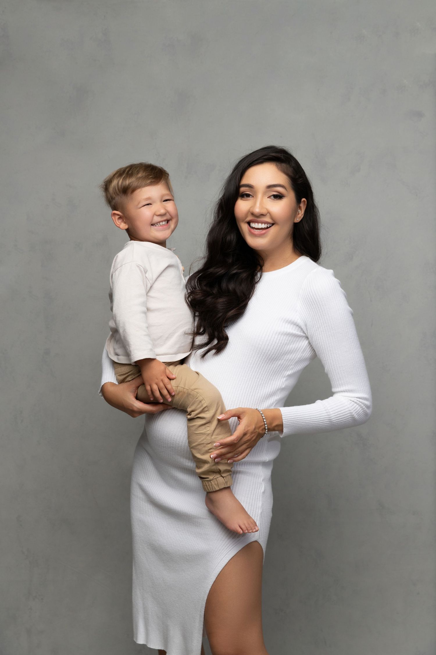 Studio portraits in sequence show joyful embraces between two people wearing white and beige against a grey background.