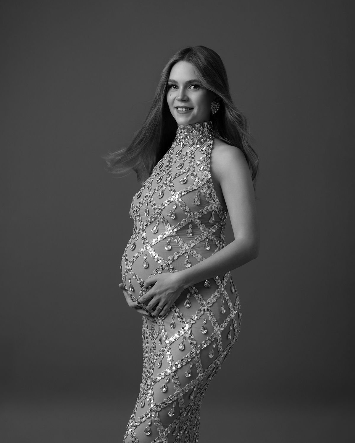 Black and white maternity portrait of an expectant mother in a sequined gown.