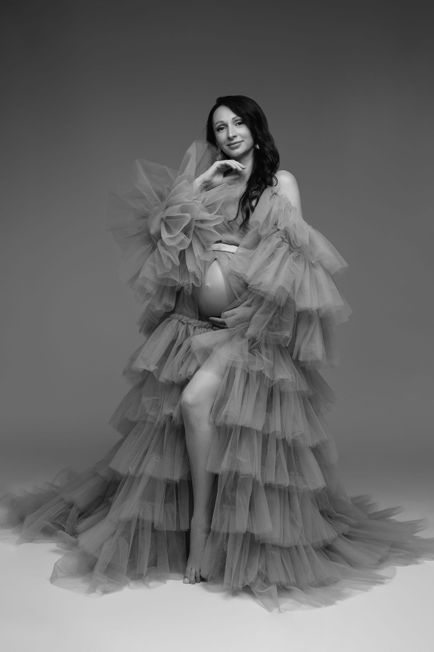 Dramatic maternity portrait featuring flowing gray tulle gown with tiered ruffles.