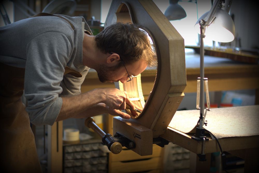 Un luthier qui travaille sur une guitare dans son atelier à Bruxelles
