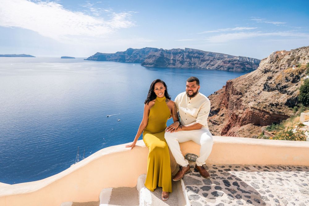 Stunning aerial view of Santorini's white buildings and blue domed churches overlooking the Aegean Sea cliffs at sunset.