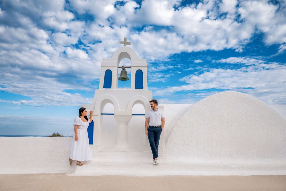 Wedding photography session on traditional white architecture with blue sky and clouds in Santorini.
