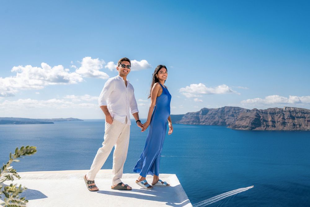 Couple enjoying scenic views of Santorini's blue domes and Aegean Sea from white terraces.