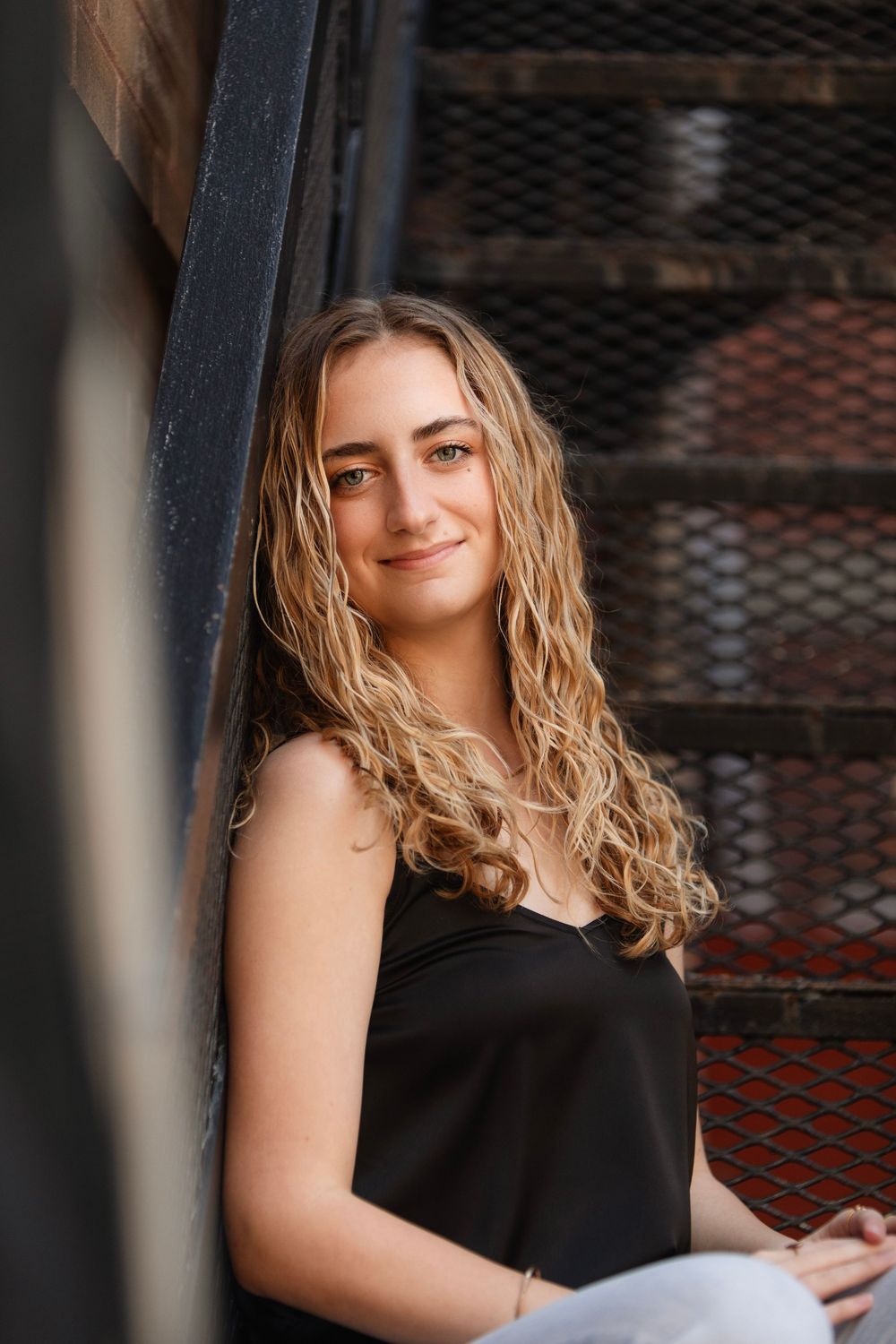 Senior graduate casual portrait against industrial metal stairs and grating.