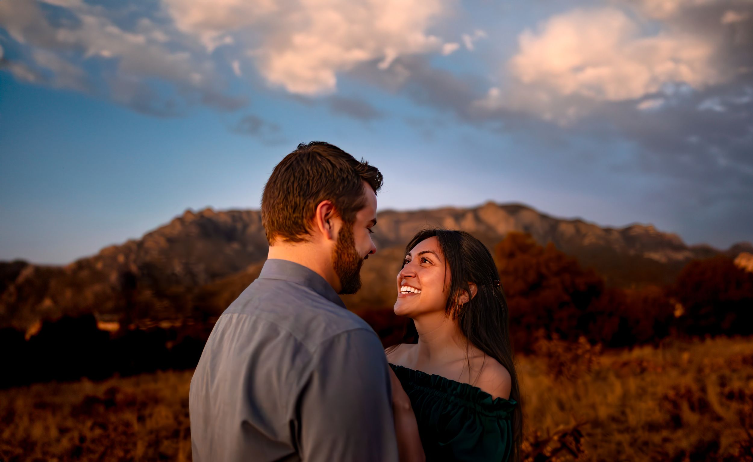 Couple embracing against mountain backdrop during golden hour sunset.