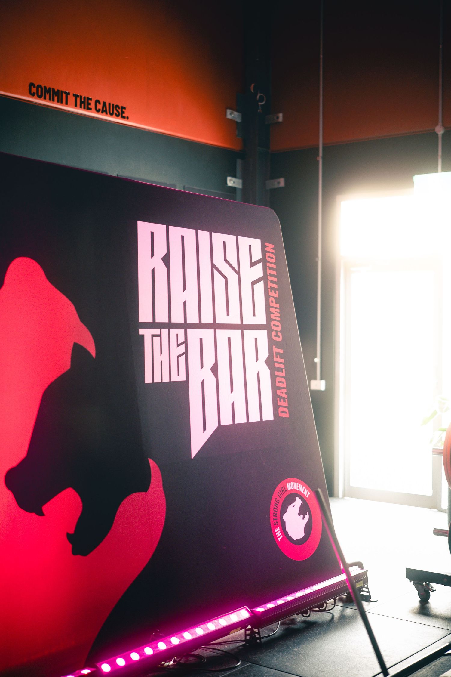 'Raise the Bar' text displayed on red illuminated backdrop with stylized design.