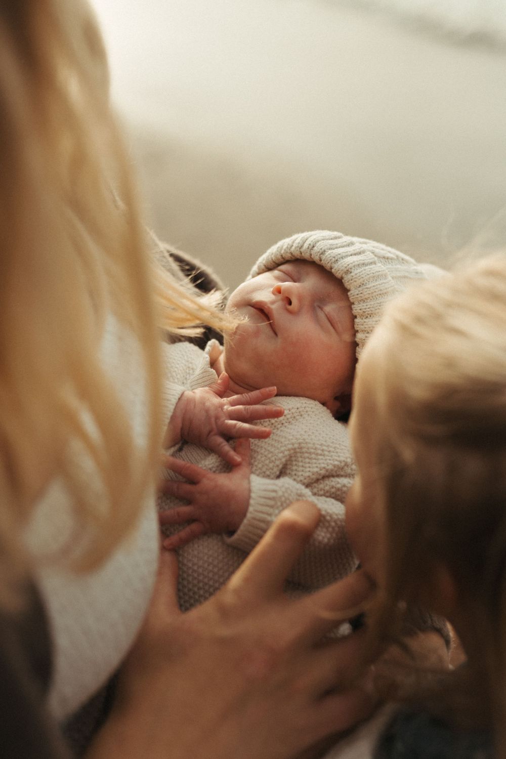 A series of intimate close-up shots showing a newborn baby being cradled and held with gentle care.