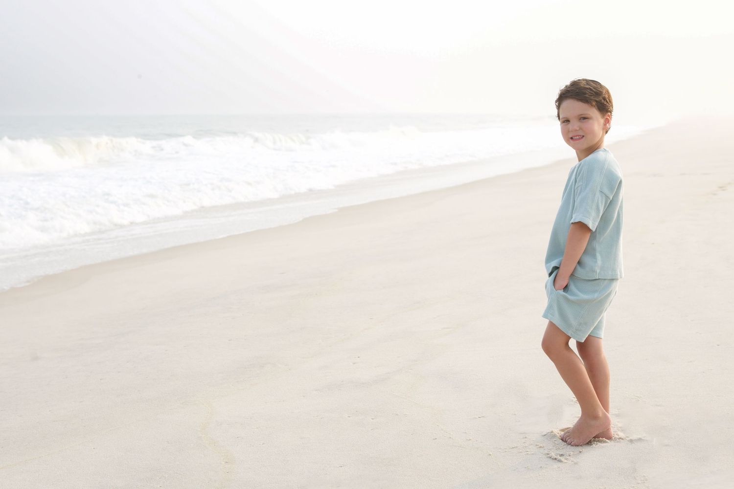 Children's feet leave footprints in the wet sand at the beach.