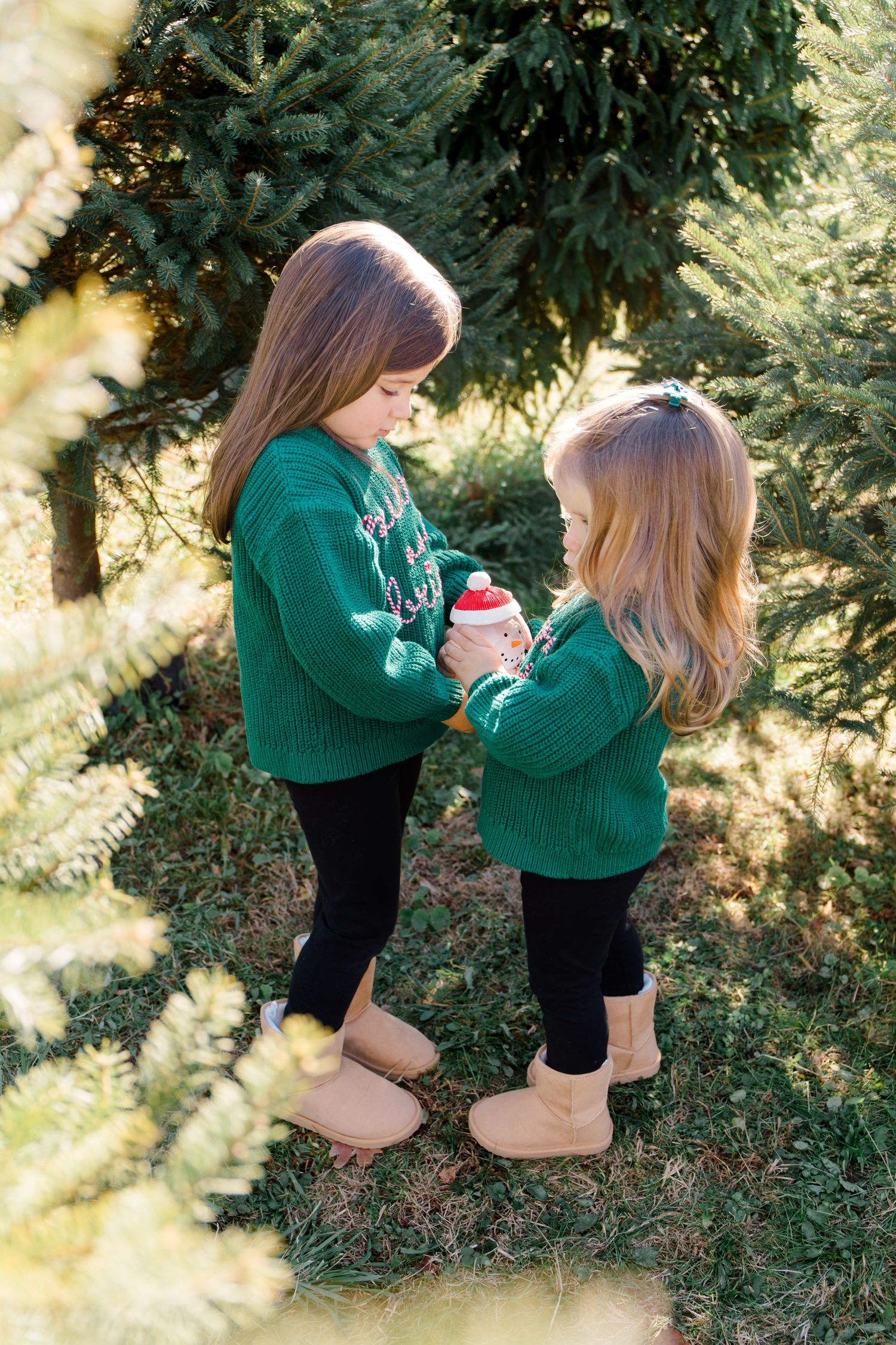 Two people in matching green sweaters decorating for Christmas outdoors.