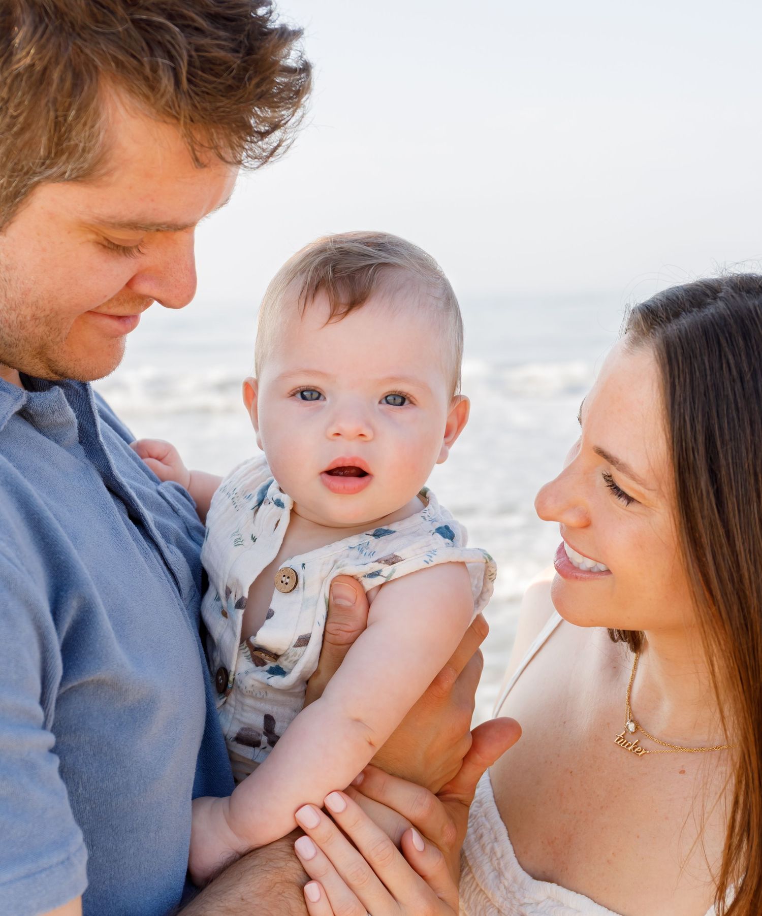 A family shares a tender moment together at the beach during sunset.