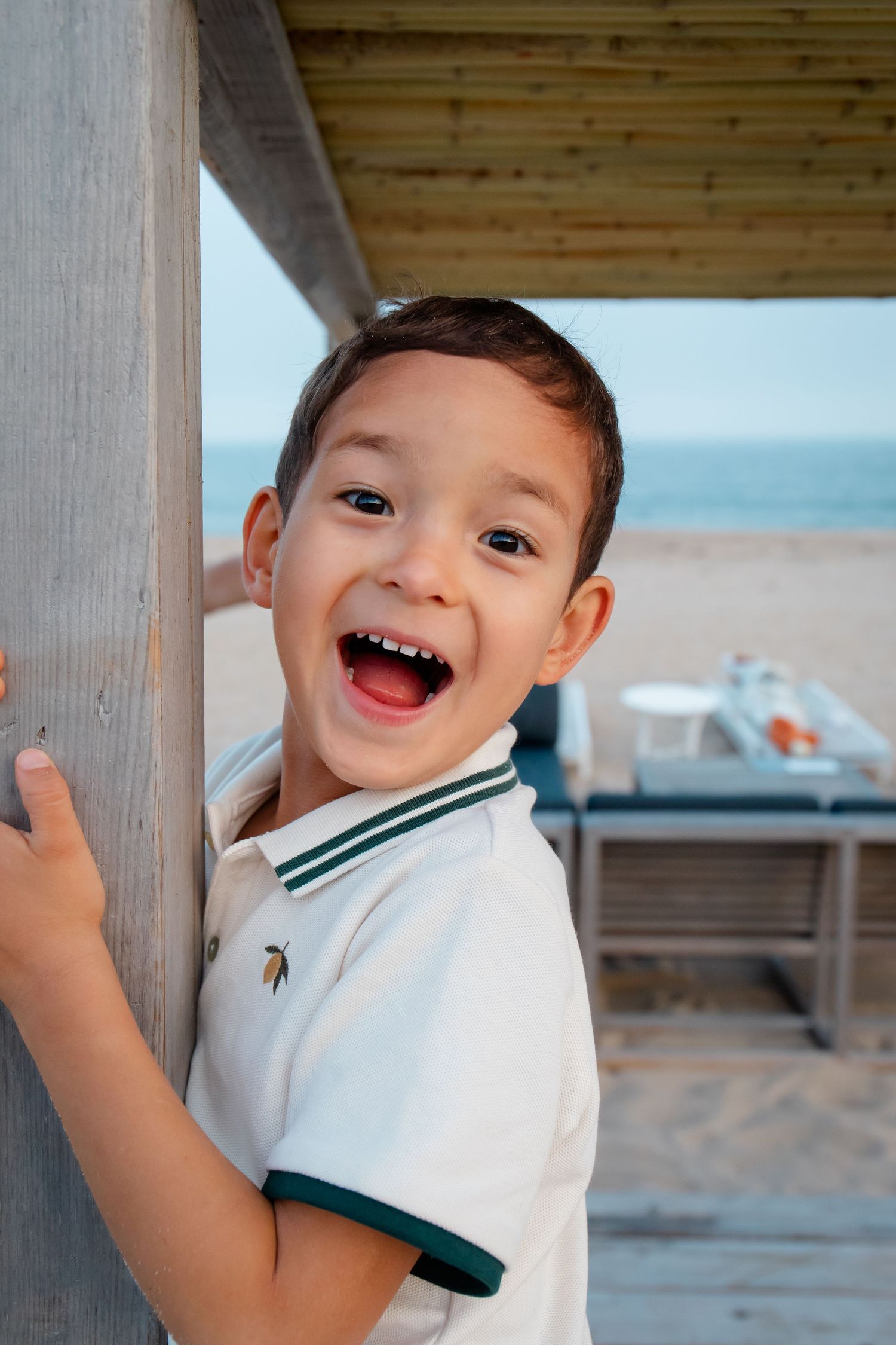 Child laughing and playing near wooden beach structure.