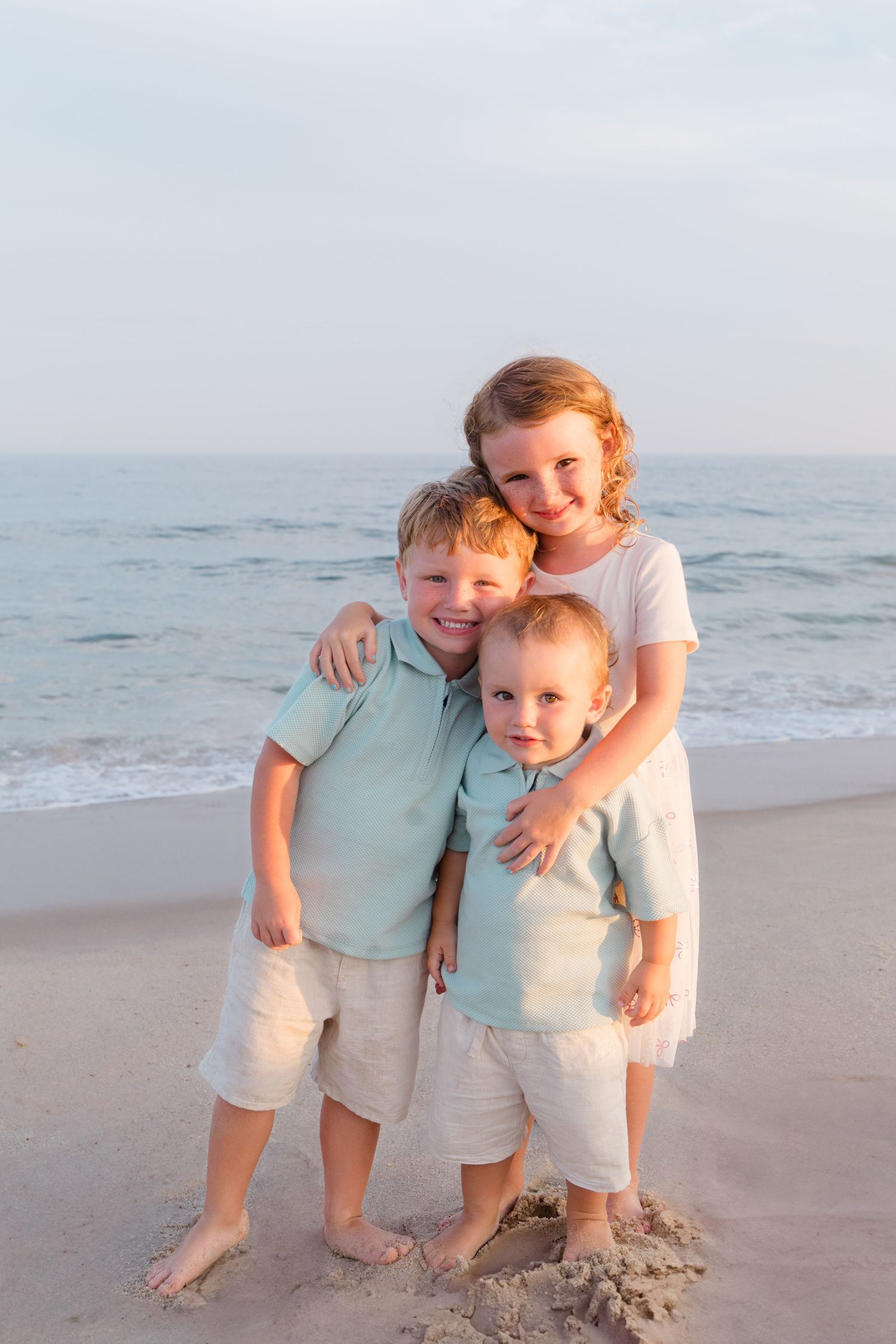 Family members share joyful moments together on a sunny beach with ocean waves in the background.