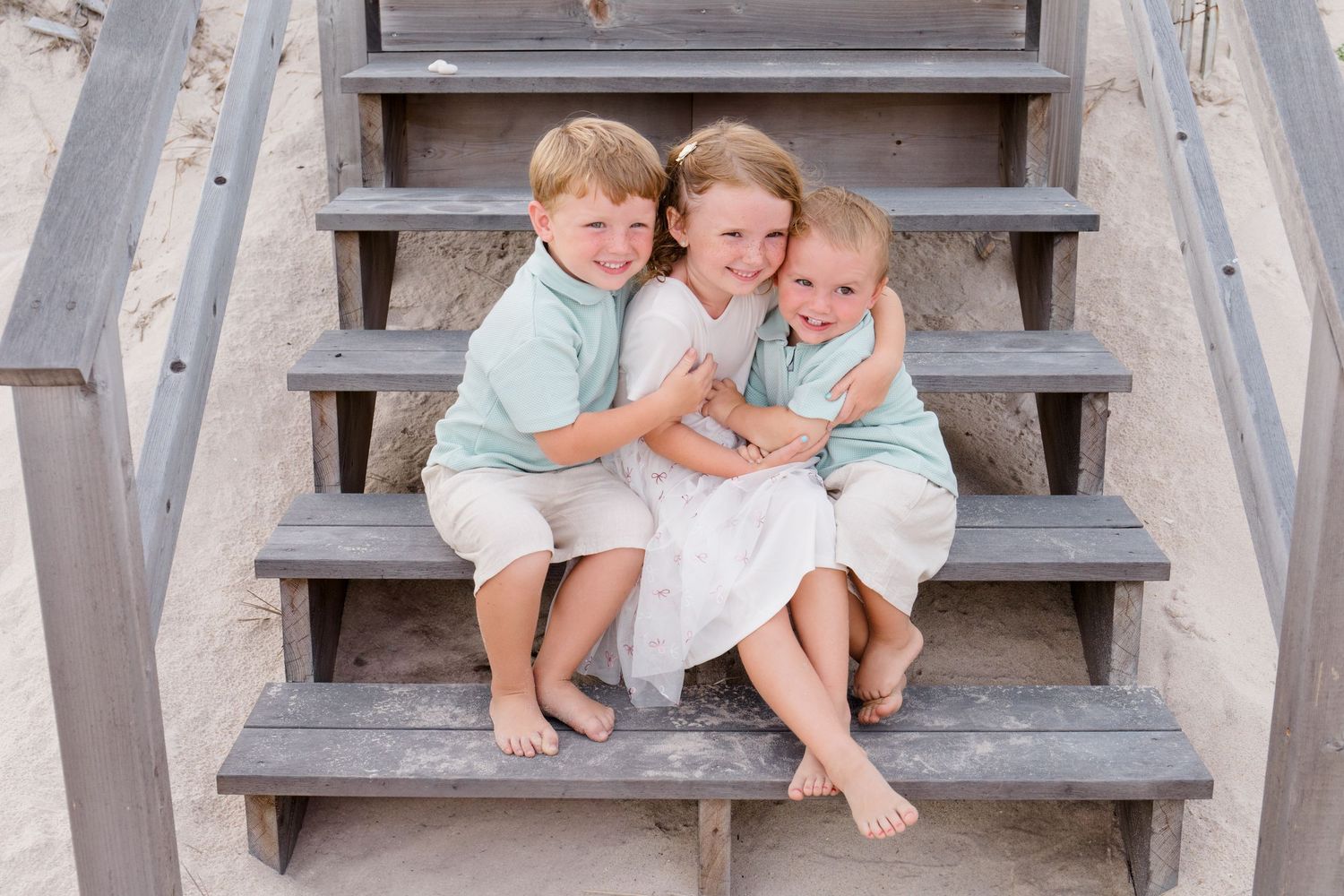 Group sitting together on wooden beach stairs during a casual outdoor photoshoot.