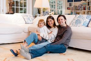 Family relaxes together on white sofa in bright living room with natural lighting.