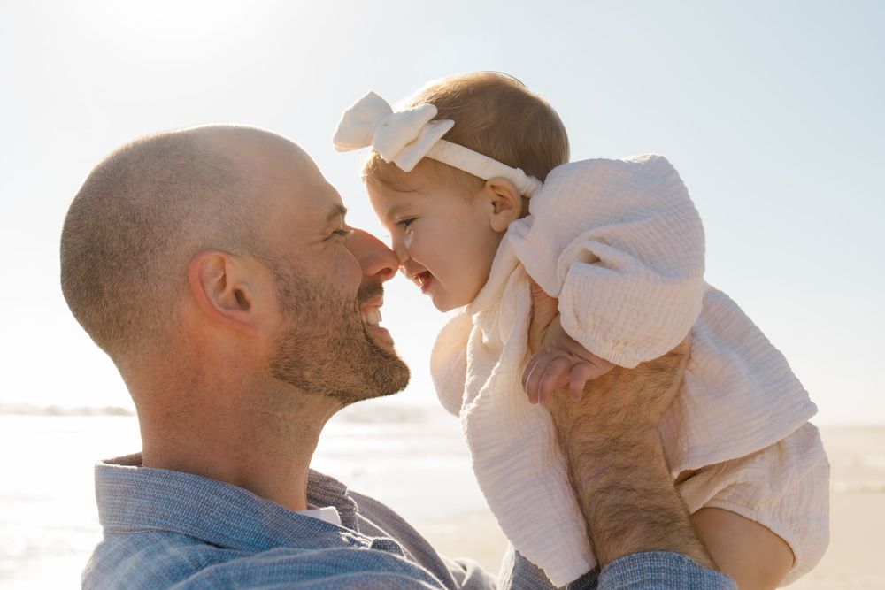 Family enjoying tender moments together during golden hour beach photoshoot.
