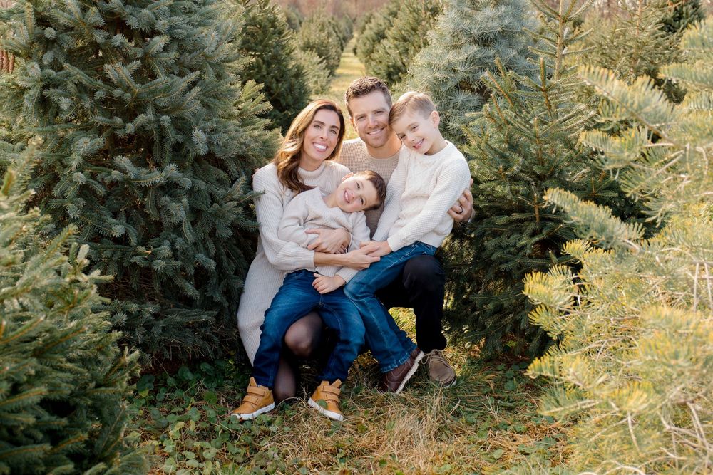A group poses together among evergreen trees during an outdoor photo session.