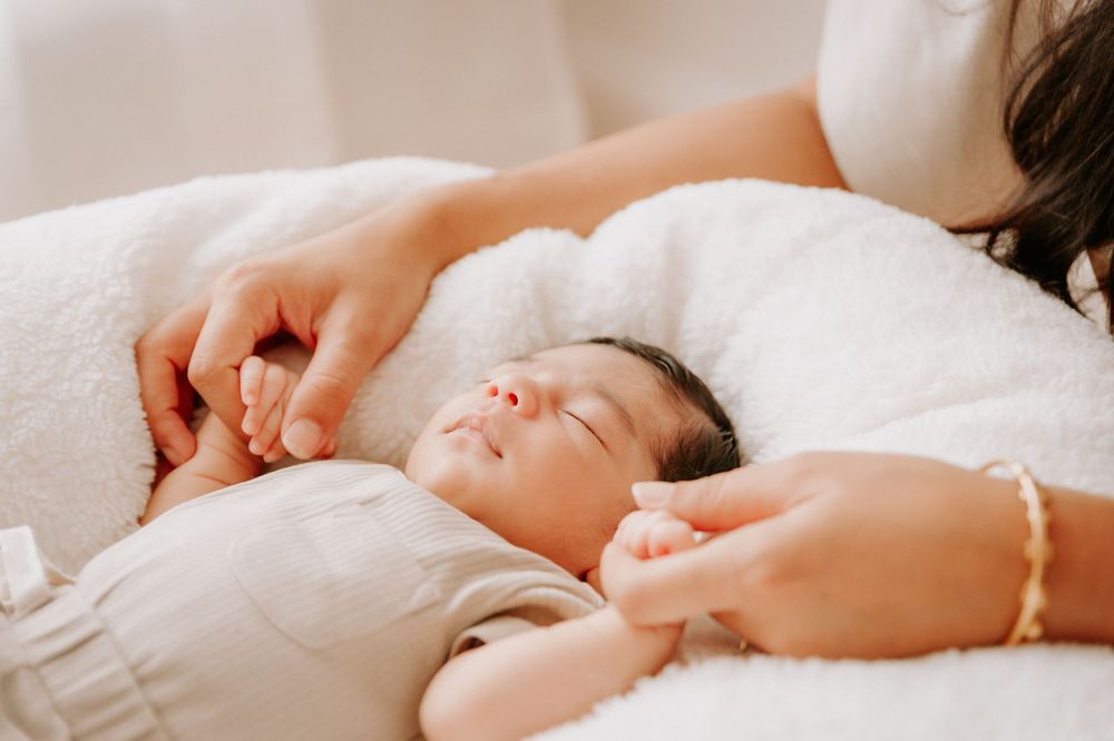 Gentle hands caressing sleeping newborn baby on white bedding.
Altona Family Photographer Melbourne