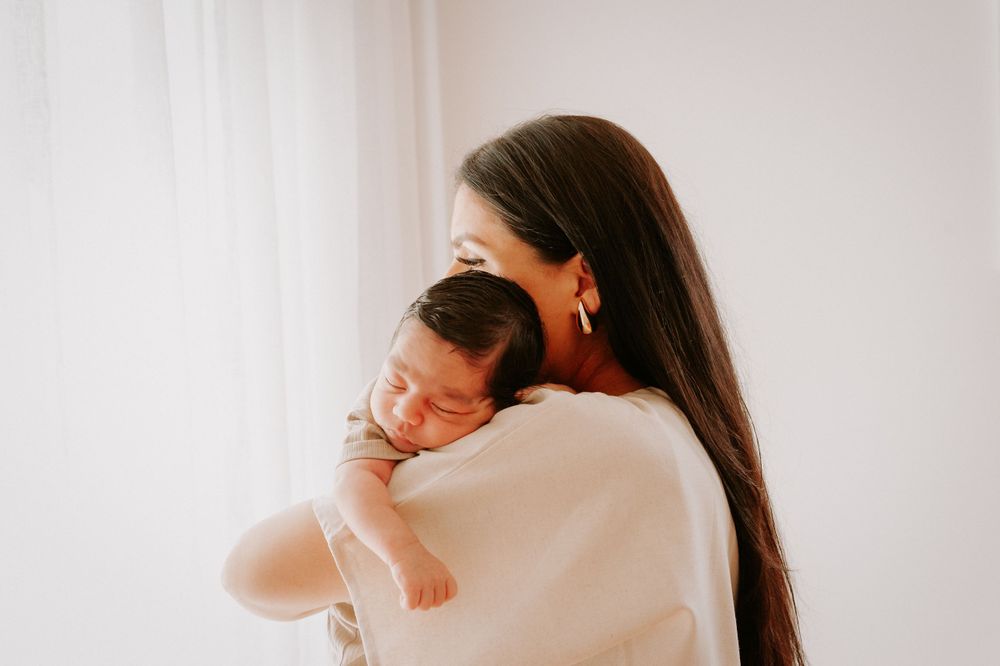Parent in white sweater cradling sleeping newborn against shoulder.
Altona Family Photographer Melbourne