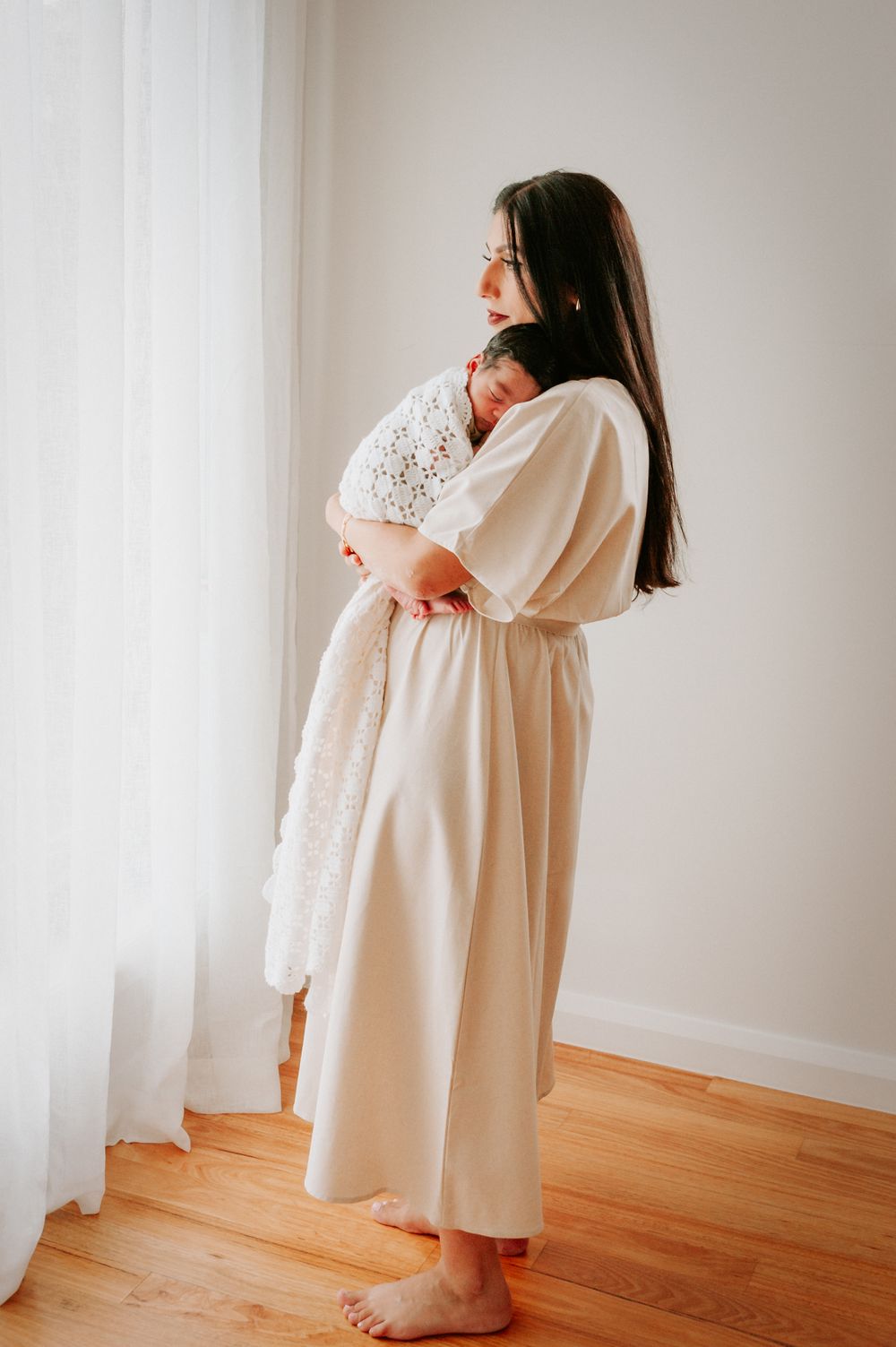 Parent in cream dress holding sleeping baby against window light.
Altona Family Photographer Melbourne