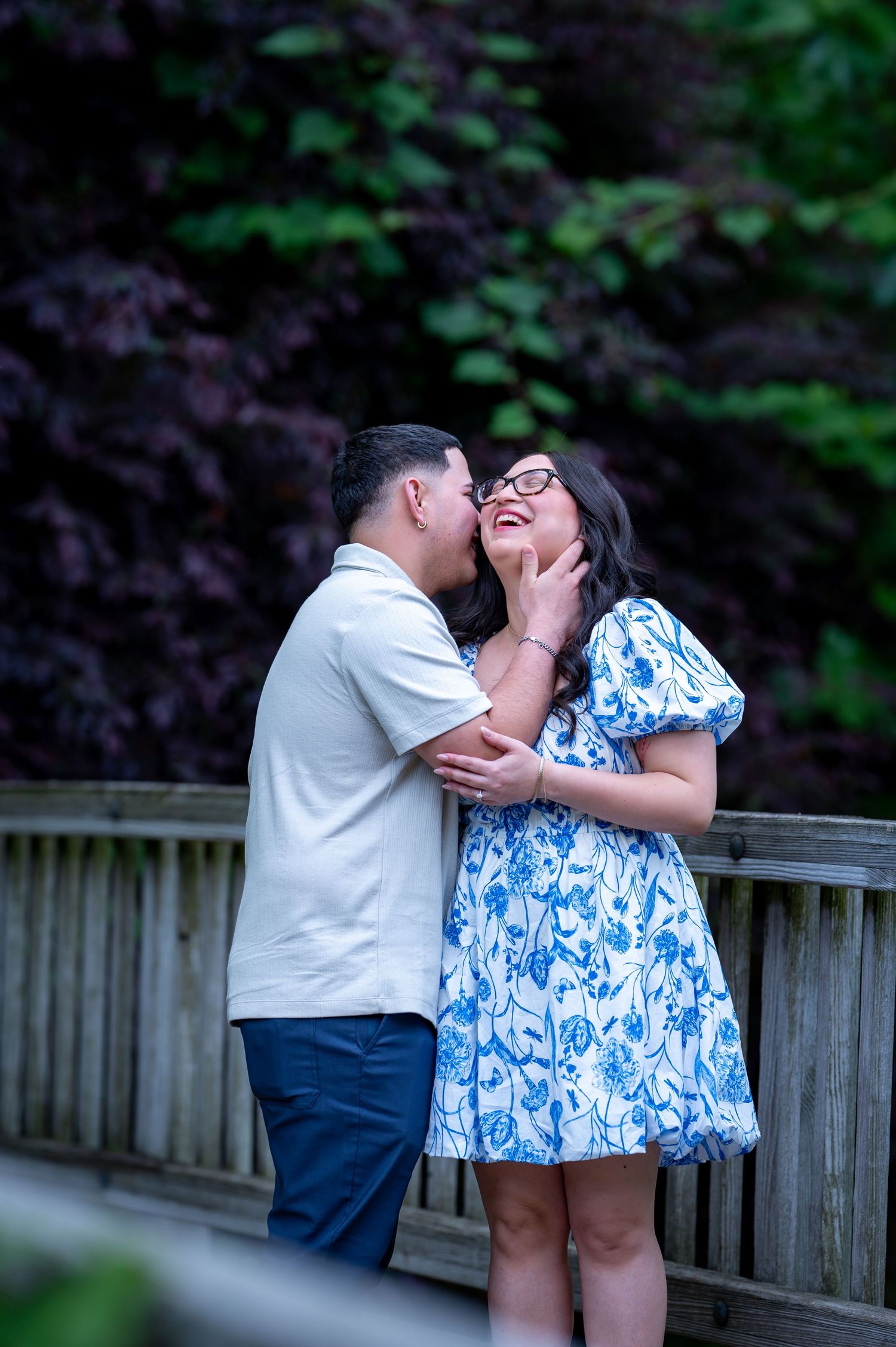 Maternity session on park bench surrounded by purple and yellow wildflowers.