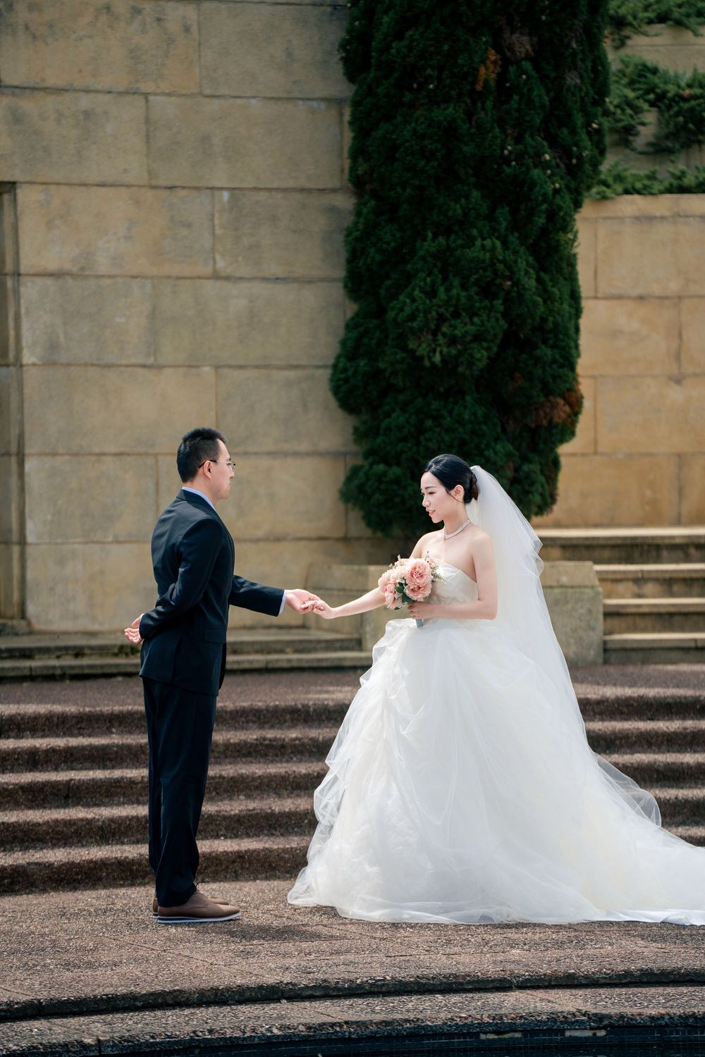 Elegant pre-wedding photo of a bride and groom holding hands at the historic Auckland War Memorial Museum.