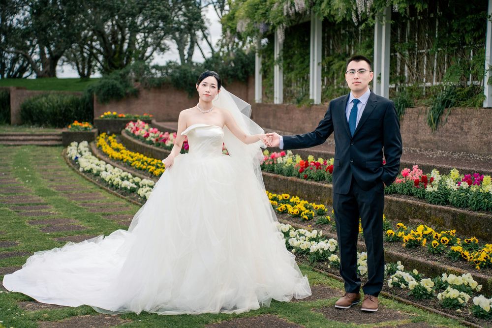 Elegant couple walking hand-in-hand through a classic formal garden for their pre-wedding shoot.
