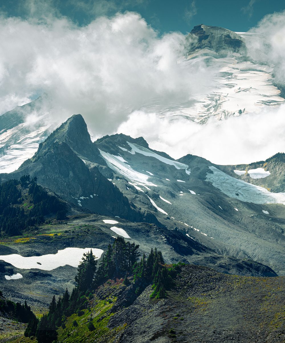Majestic snow-capped mountain peaks with dramatic clouds and green valleys below.