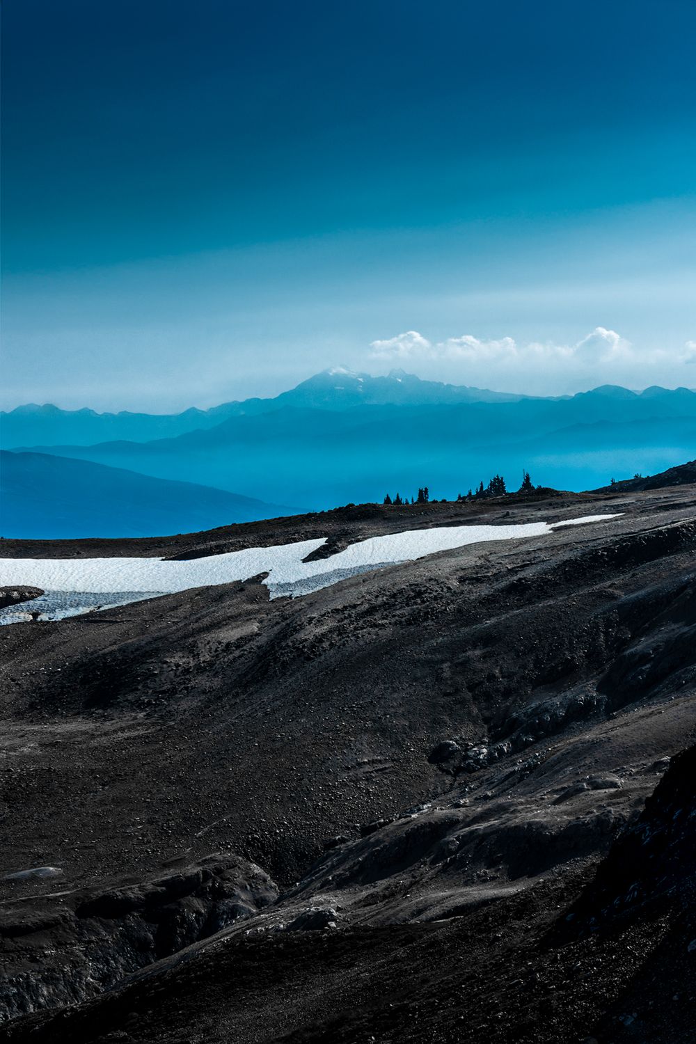 Snowy mountain slopes with layers of blue ridges extending to the horizon.