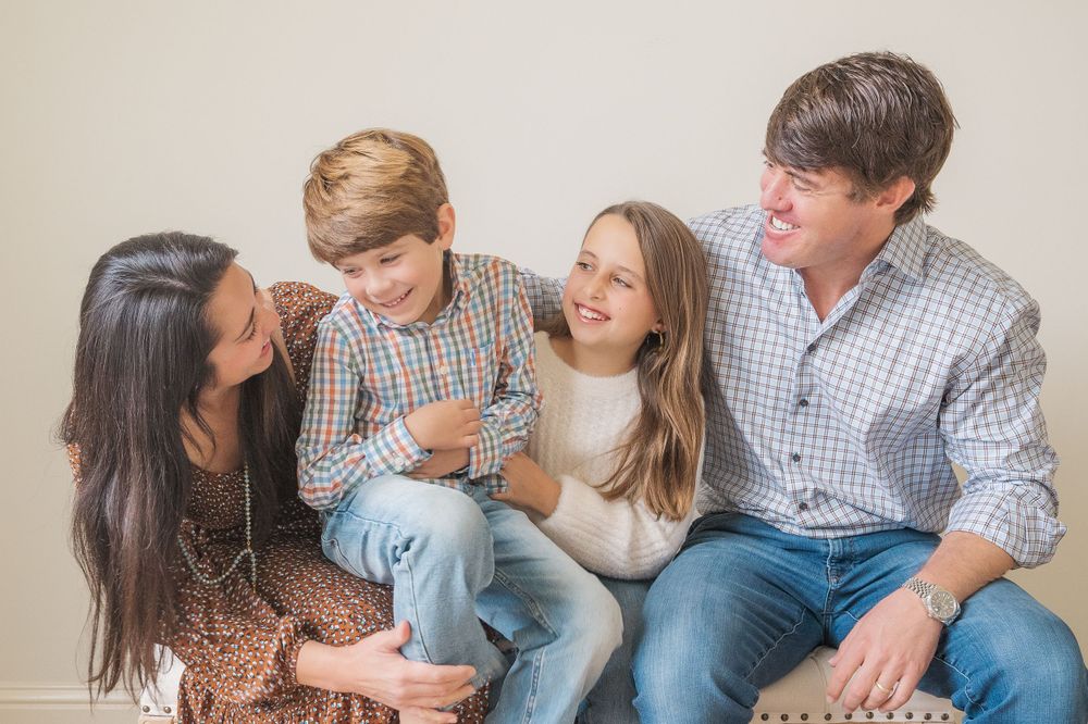 A family sitting close together on a couch sharing a warm moment in casual attire.