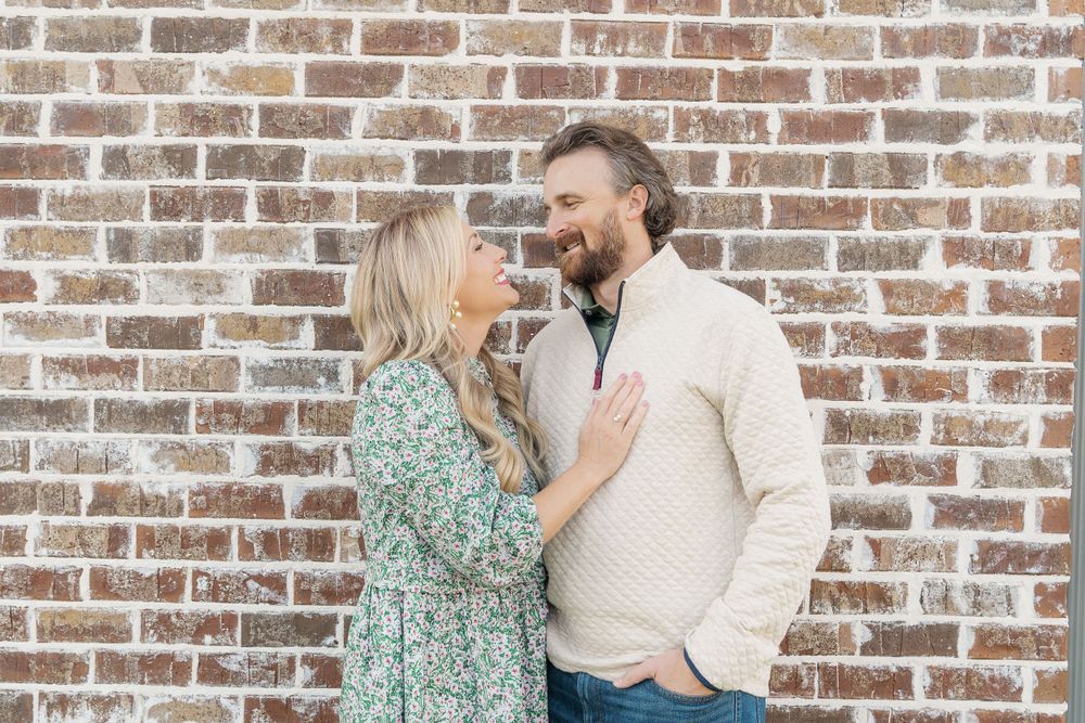 A couple sharing an intimate moment against a rustic brick wall backdrop.