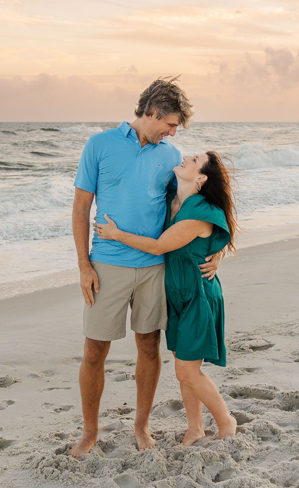 A romantic couple embracing on a sandy beach at sunset.