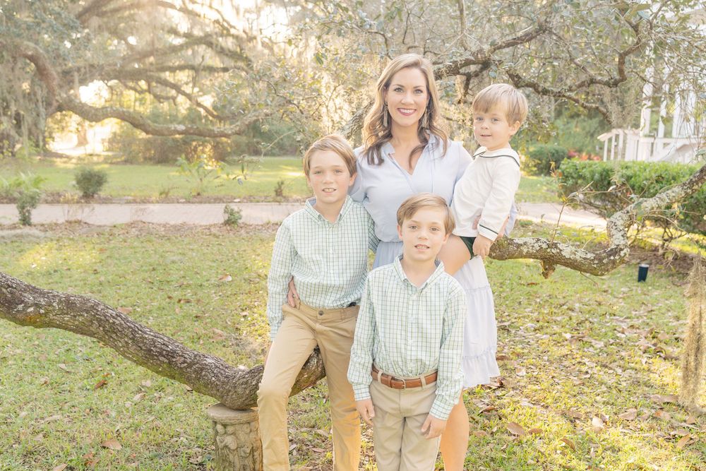 A group in coordinated outfits posing by a tree branch in a sunny outdoor setting.