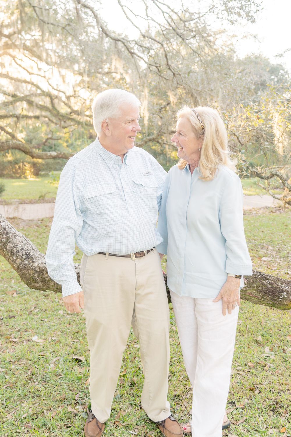 A couple in light colored casual clothing sharing a happy moment outdoors.