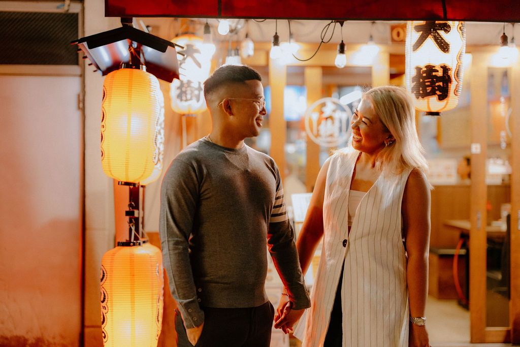 Couple enjoying an intimate moment in a Japanese restaurant decorated with warm glowing lanterns.