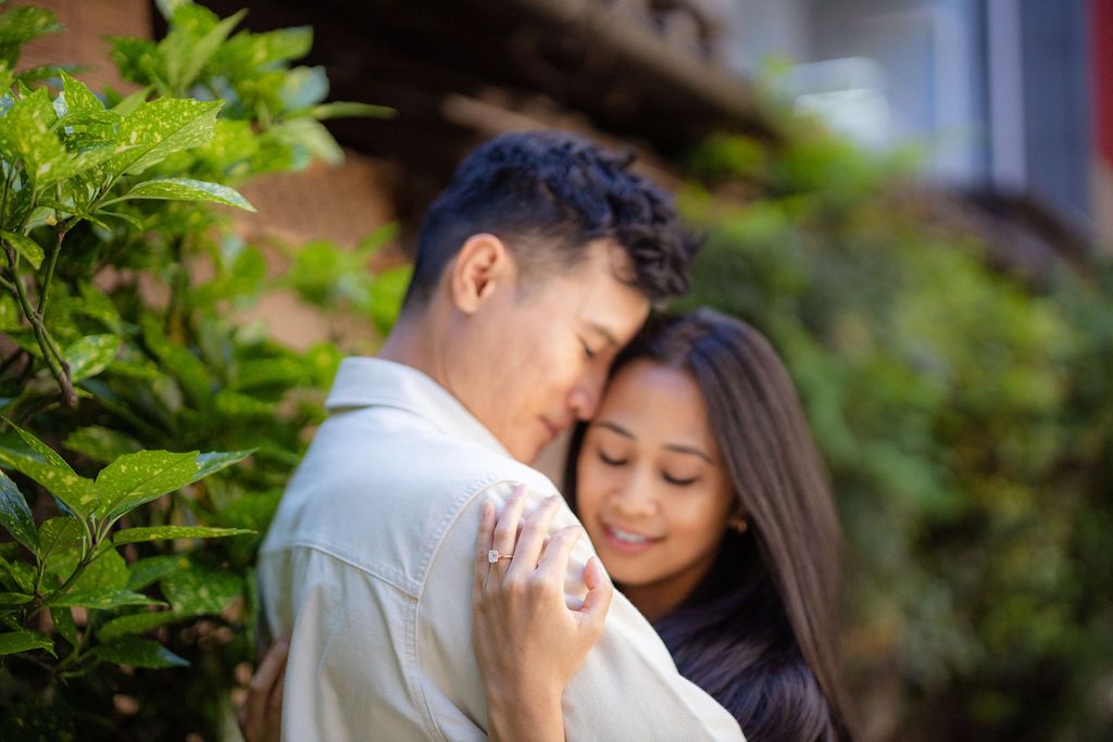A romantic embrace amidst lush green foliage in a Japanese garden setting.