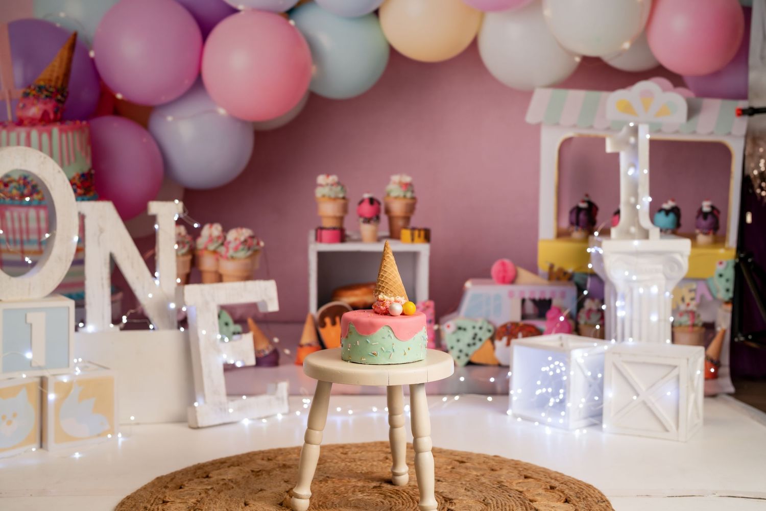 Pastel balloon garland and party decorations against pink wall for birthday celebration.