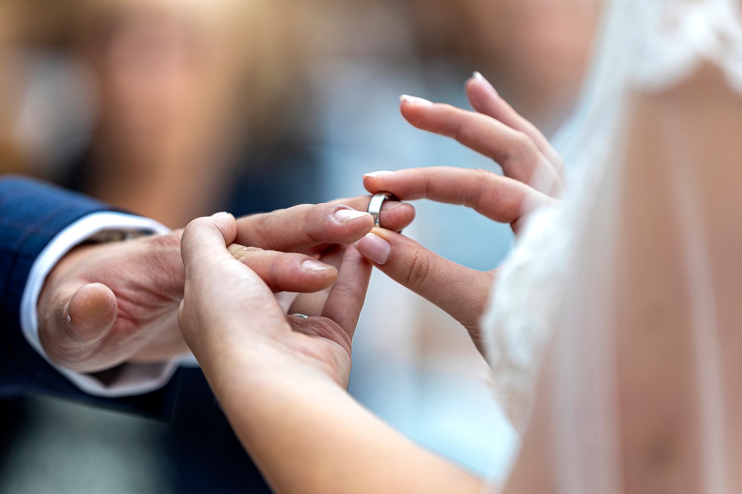 bride putting ring onto grooms finger