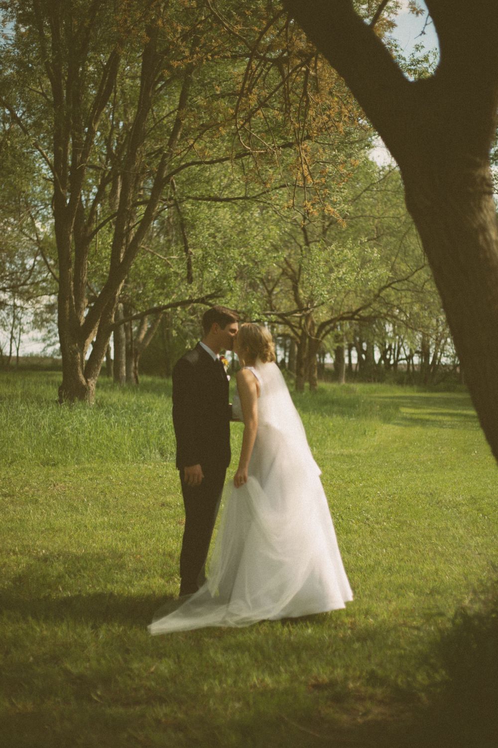 A tender wedding moment captured in a garden setting with a couple in formal attire.