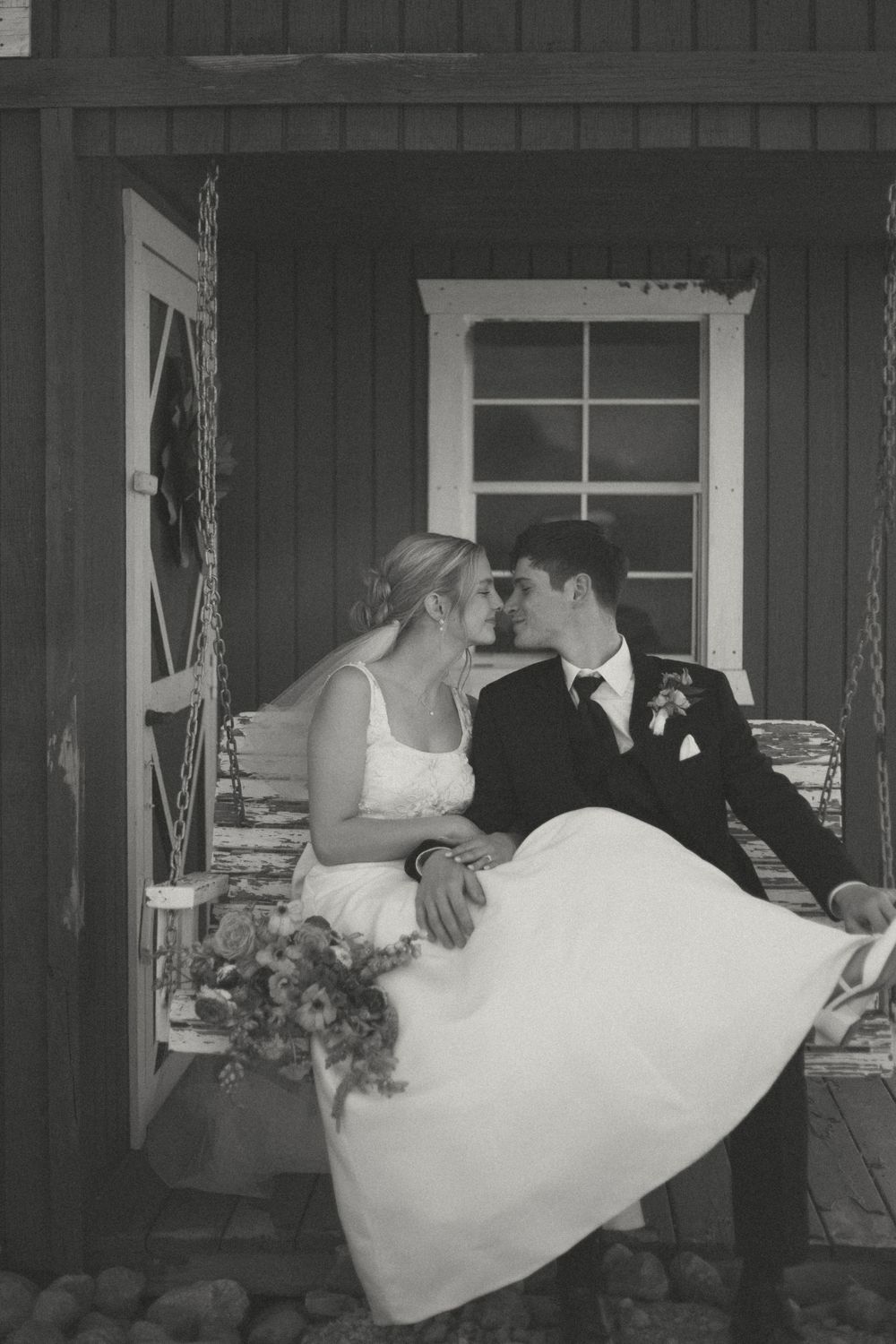 A classic black and white wedding photo on a rustic porch with a vintage aesthetic.