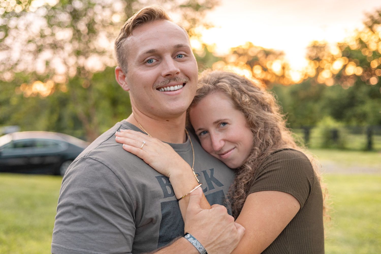 Couple embracing in a park during golden hour sunset.