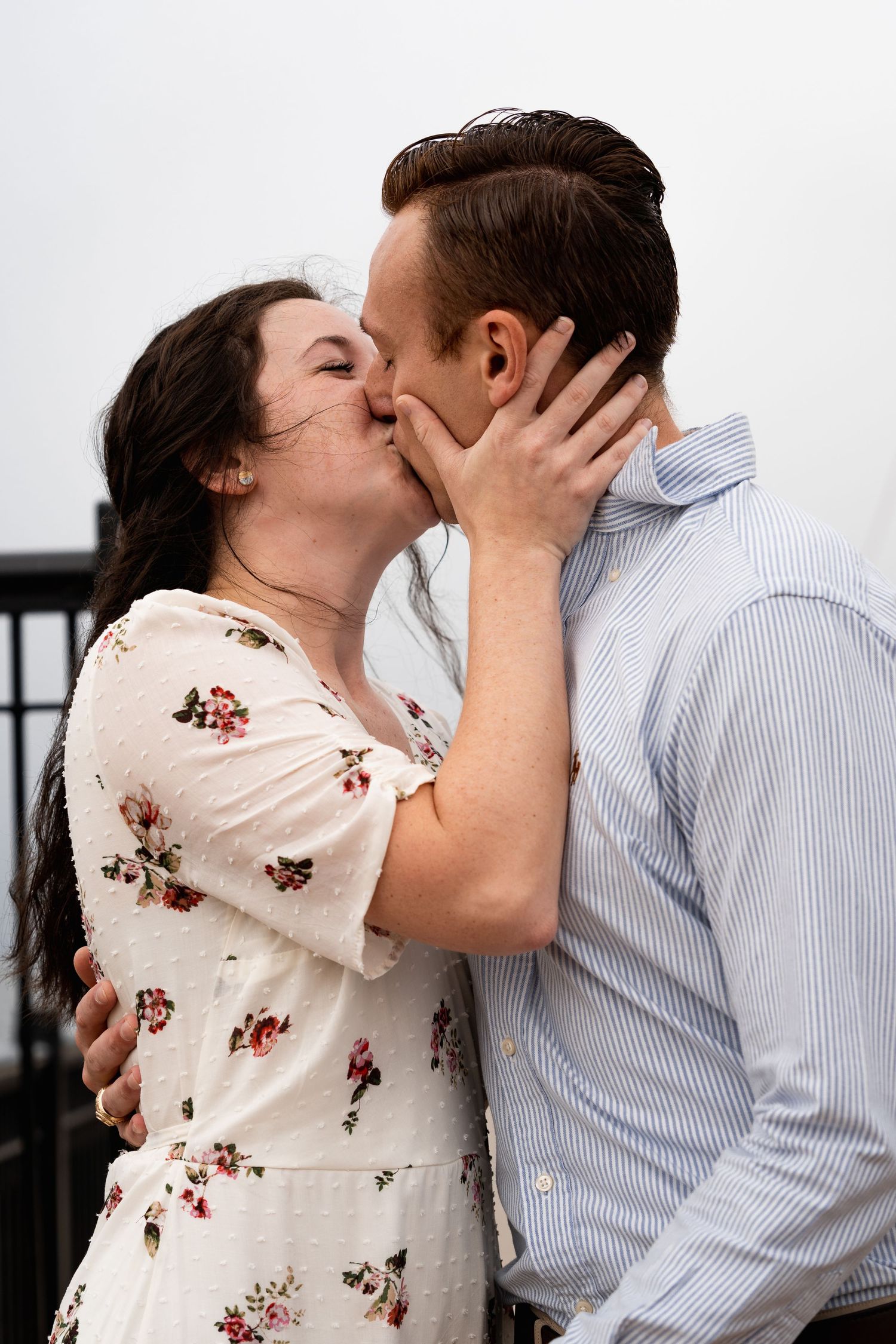 Sweet romantic kiss between couple on outdoor deck.