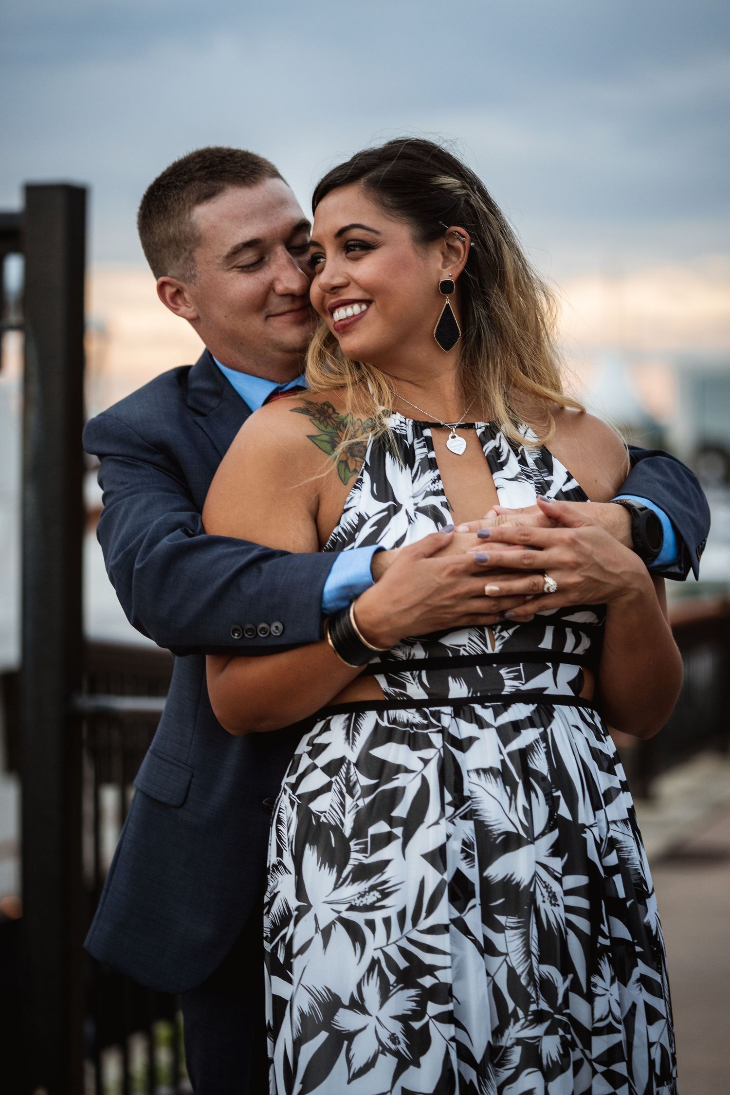 Romantic couple embracing outdoors at sunset with woman wearing floral dress.
